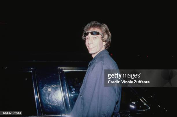 British singer-songwriter Robin Gibb , with a pair of sunglasses raised against his forehead, as he turns to smile before getting in a waiting car,...