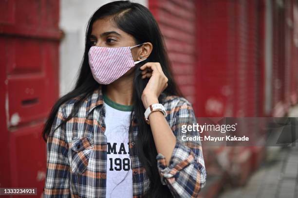 young woman wearing protective mask smiling at camera - protective face mask side stock pictures, royalty-free photos & images