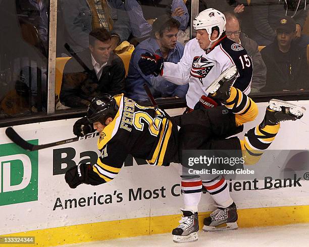 Boston Bruins defenseman Andrew Ference takes a big hit along the boards from Columbus Blue Jackets right wing Derek Dorsett during the first period....