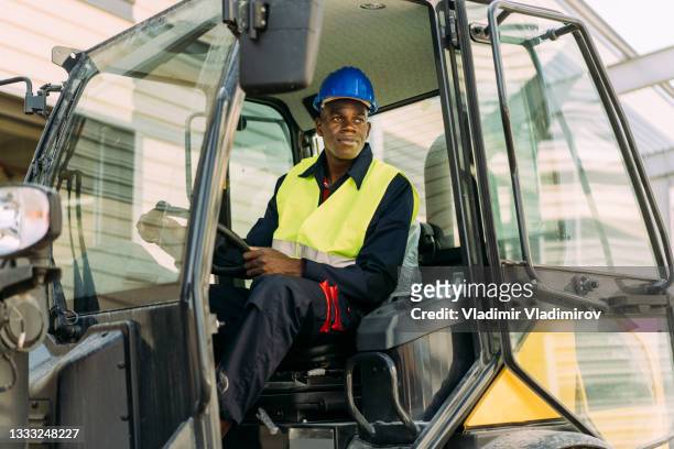 afro-american excavator driver sitting in his machine - construction vehicles bildbanksfoton och bilder