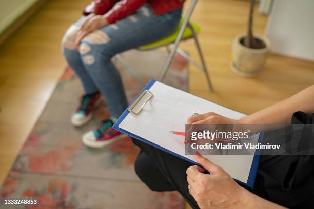 una psicologa che prende appunti mentre parla con una studentessa durante una terapia mentale - anoressia foto e immagini stock