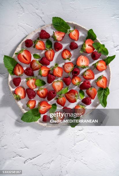 strawberries cut and raspberries berry fruits with mint leaves on white plate on rustic whitewashed background - juicy raspberry stock pictures, royalty-free photos & images