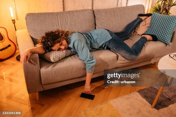 müde junge frau schläft zu hause auf der couch - chronic fatigue stock-fotos und bilder