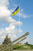 flag of Ukraine on a background of blue sky and divisional guns