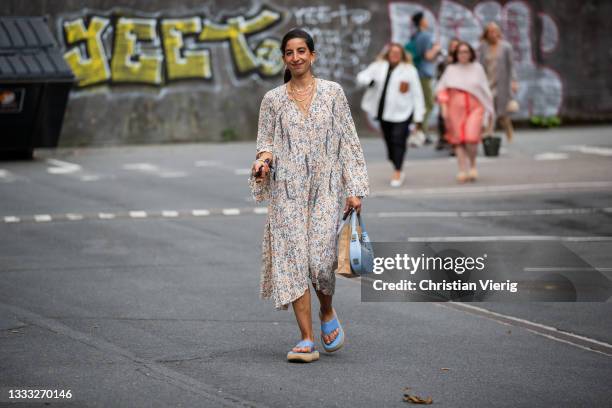 Guest is seen wearing dress with floral print, blue sandals on August 09, 2021 in Copenhagen, Denmark.