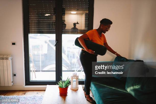young woman arranging things in her new apartment - new sofa stock pictures, royalty-free photos & images