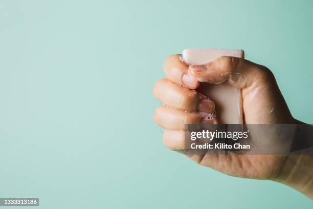 female hand holding wet soap with against green background, eco friendly concept - bar of soap stock pictures, royalty-free photos & images