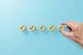 Checklist and check mark concept. Check mark on wooden blocks on light blue background