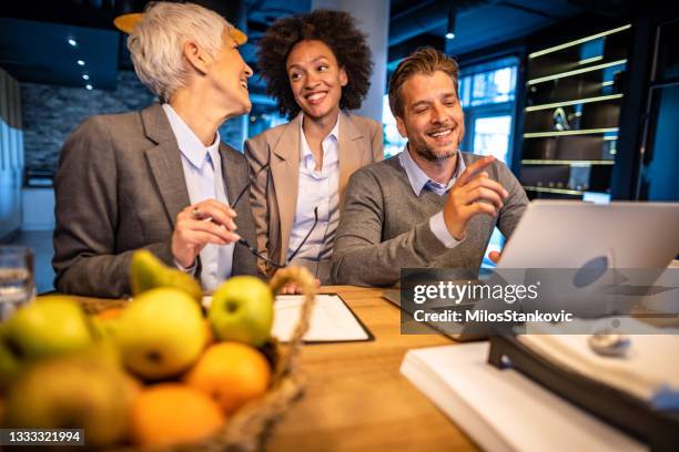 glückliche geschäftskollegen, die bei der arbeit am laptop zusammenarbeiten - business talk sit men stock-fotos und bilder