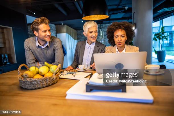 glückliche geschäftskollegen, die bei der arbeit am laptop zusammenarbeiten - business talk sit men stock-fotos und bilder