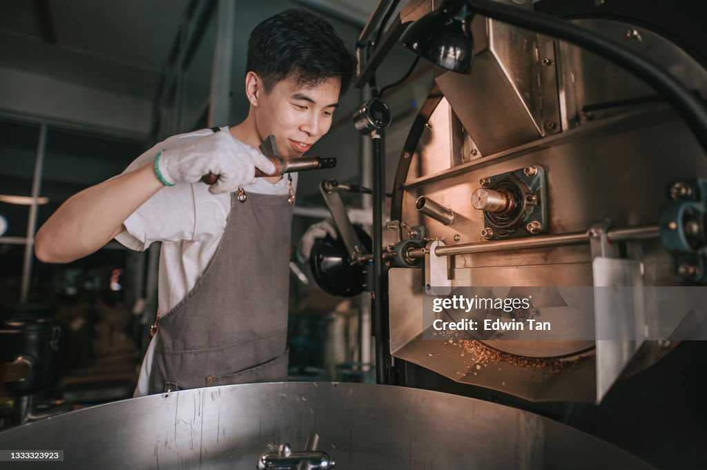 Raftsperson chino asiático sosteniendo Trier extrayendo granos de café de tostador de café Tostado Granos de café crudos oliendo a comprobación