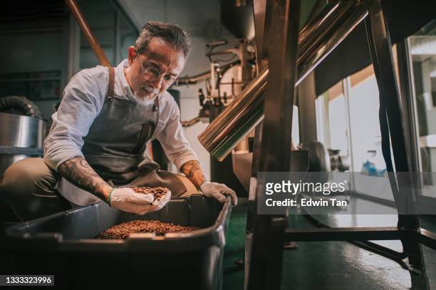 asian chinese senior man craftsperson examining roasted coffee bean de-stoning stone removal process after spinning out from cooling process in his factory - craft beer 個照片及圖片檔
