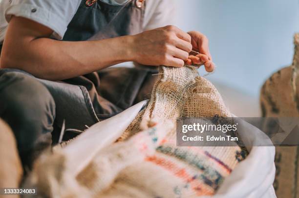 close up warehouse worker untying raw coffee bean sack - eerlijke handel stockfoto's en -beelden