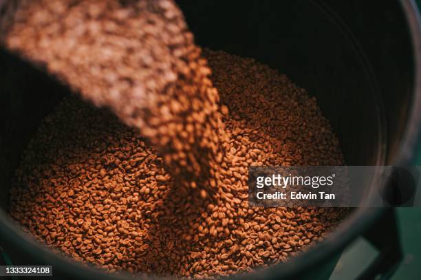 スクープの重み付けとブレンドで貯蔵ペールに生のコーヒー豆を注ぐ高角度のビュー - 焙煎 ストックフォトと画像