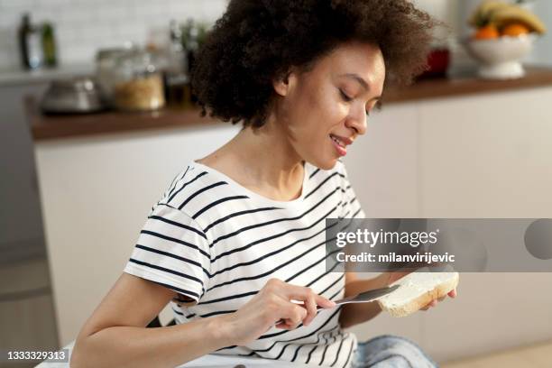 beautiful young african woman eating sandwich. - making a sandwich stock pictures, royalty-free photos & images