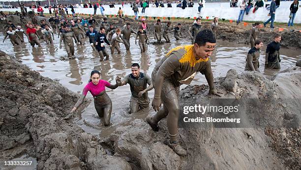 Participants slog through the mud mile obstacle during the Tough Mudder endurance challenge at Raceway Park in Englishtown, New Jersey, U.S., on...