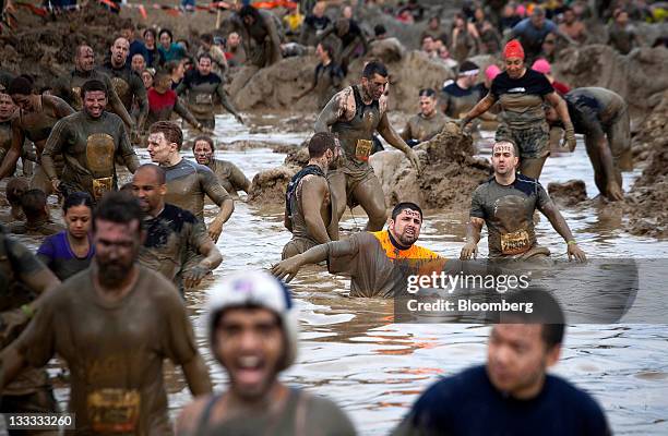 Participants slog through the mud mile obstacle during the Tough Mudder endurance challenge at Raceway Park in Englishtown, New Jersey, U.S., on...