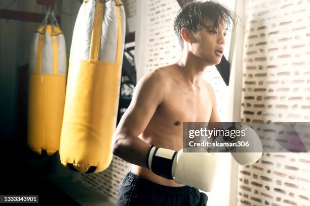 asian sport man teenager amateur boxer looking motivate practice strong hook punch with yellow punch bag - amateur theater stock pictures, royalty-free photos & images