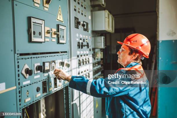 senior woman, engineer-technician, is operating complex equipment on electrical dispatching station, checking system status, and adjusting parameters of the power grid. - old factory stock pictures, royalty-free photos & images