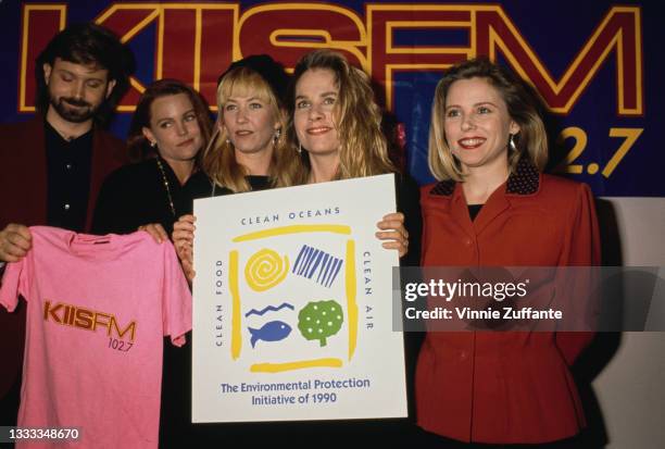 An unspecified man holds a pink 'KIISFM 102.7' t-shirt, alongside members of American New Wave band The Go-Go's at the studios of KIIS-FM in Los...