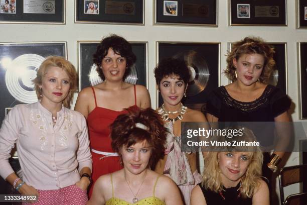 American New Wave band The Go-Go's pose in front of presentation discs on a wall at the offices of A&M Records in Santa Monica, California, 1983.