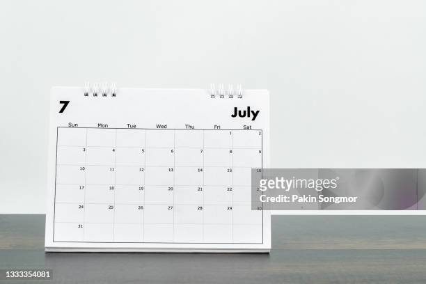 calendar desk 2022 july month for organizer to plan and reminder on wooden table with white color old grunge wall concrete background. - july stock pictures, royalty-free photos & images