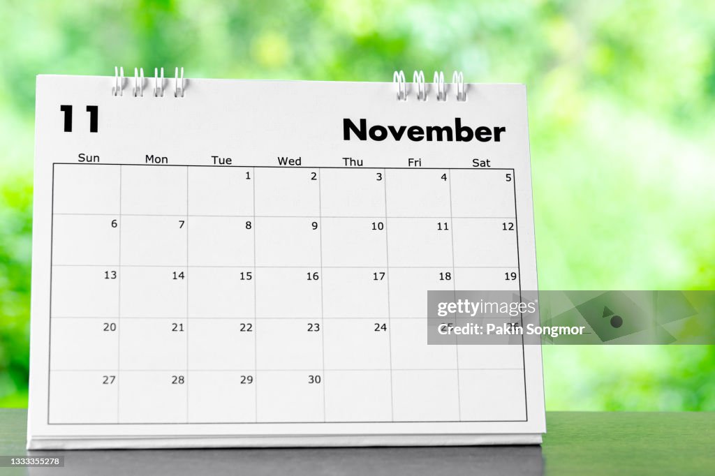Calendar desk 2022 November month for organizer to plan and reminder on wooden table with nature background.