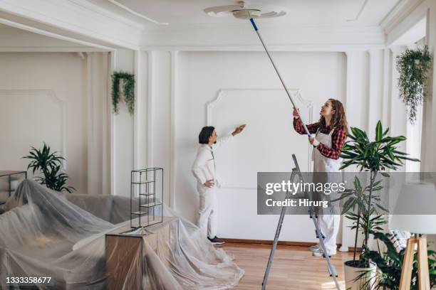 young couple painting walls together - painting ceiling stock pictures, royalty-free photos & images