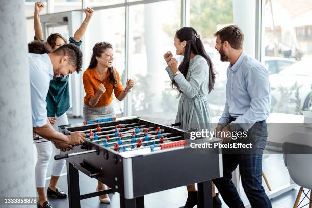 coworkers playing table football - employee wellbeing stock pictures, royalty-free photos & images