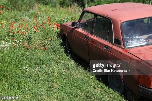 old abandoned red soviet car in flower field - abandoned car - fotografias e filmes do acervo