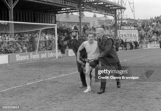 Newcastle United supporter wearing a black and white kilt, is escorted off the pitch by two policeman as Newcastle are promoted back to the First...