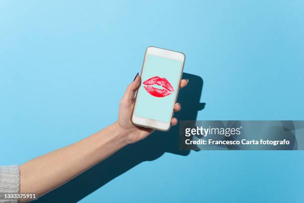 woman's hand shows her smartphone with lipstick kiss - lippenstift afdruk stockfoto's en -beelden