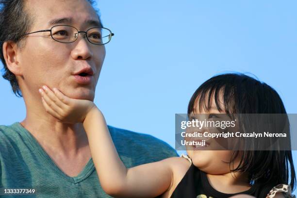 child putting her hand on father chin smiling bonding quality time - kid putting finger in mouth stock-fotos und bilder