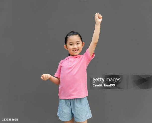 little girl raise arm on gray background - pink shirt stock pictures, royalty-free photos & images