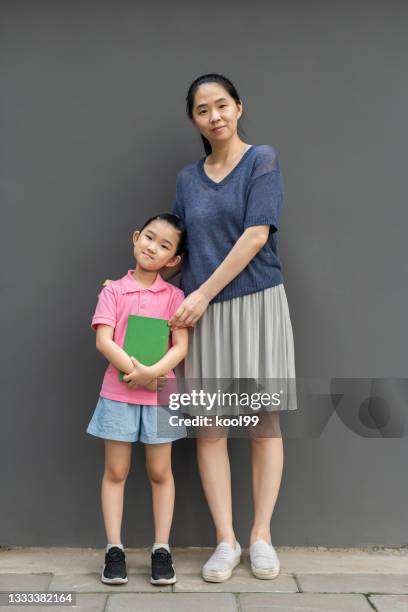 mutter und tochter stehen auf grauem hintergrund - teacher studio portrait stock-fotos und bilder