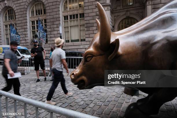People walk by the Wall Street Bull near the New York Stock Exchange on August 10, 2021 in New York City. Markets were up in morning trading as...