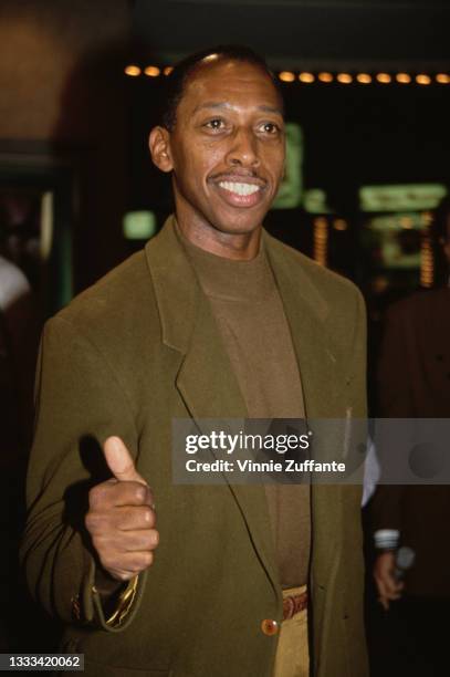 American singer-songwriter Jeffrey Osborne wearing a brown sweater beneath an olive green blazer, giving a thumbs up, location unspecified, circa...