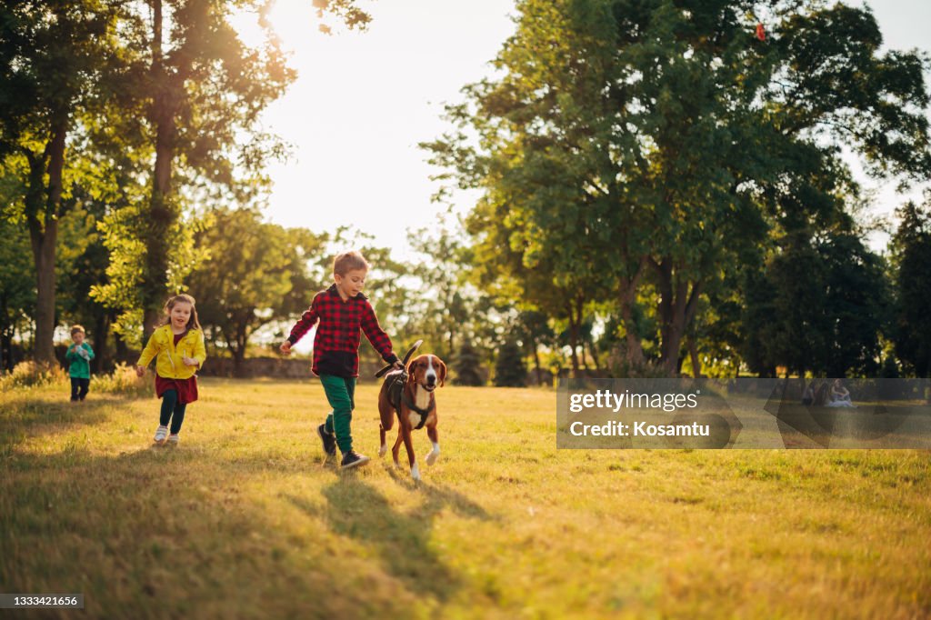Excited and playful kids, running with their hound dog, having an amazing adventure together