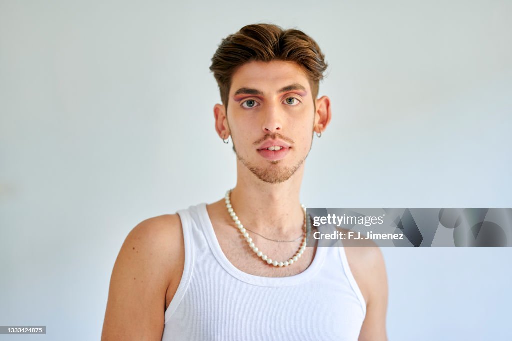Portrait of man with makeup in front of white wall