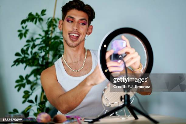 man putting on makeup in front of mobile phone using ring of light - influencer fotografías e imágenes de stock