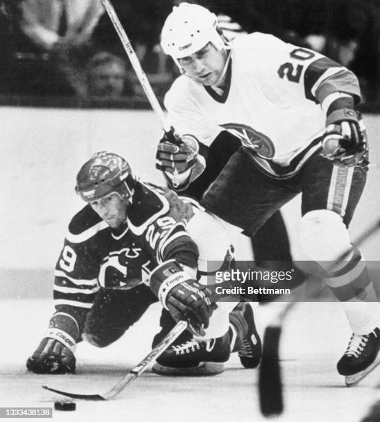 Jan Ludvig of the New Jersey Devils and Mats Hallin of the New York Islanders scramble for the loose puck on the ice.