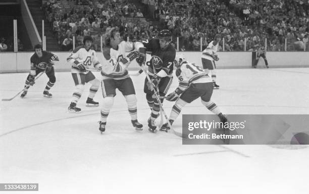 The Flames defensiveman, Randy Manery and Islanders leftwing, Germain Gagnon get into a shoving bout for control of the puck that bounced up between...