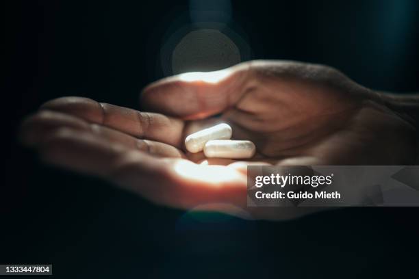 hand holding 2 pills in sunlight. - gelule photos et images de collection