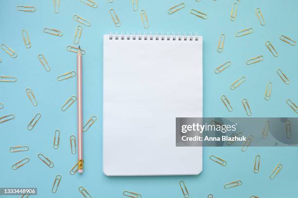 note pad with blank white page over blue background. back to school concept. pencil and golden paper clip. - note pad on table stock pictures, royalty-free photos & images