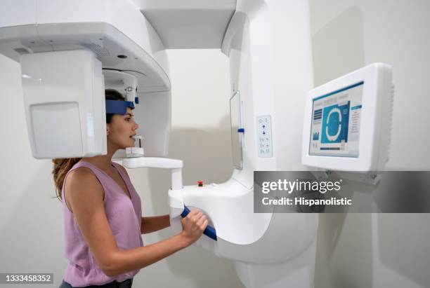 woman getting an x-ray of her teeth at a dental clinic - equipamento de exame médico por imagem de diagnóstico imagens e fotografias de stock