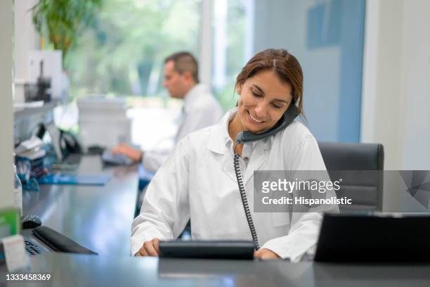 receptionist working at a doctor's office and talking on the phone - assistente stockfoto's en -beelden