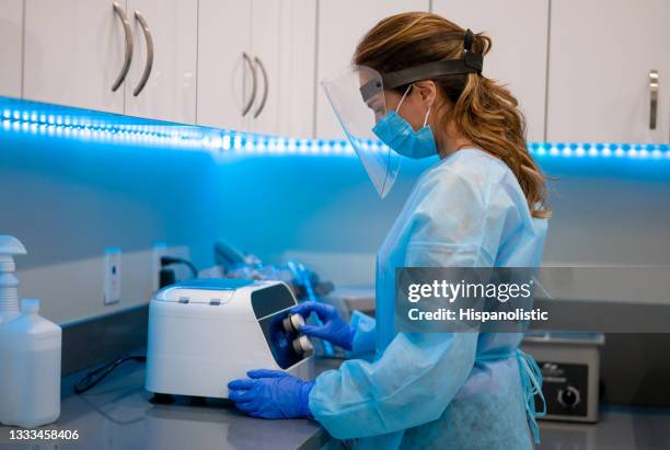 dental hygienist wearing ppe and sterilizing medical equipment - biosecurity stock pictures, royalty-free photos & images