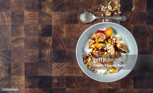 breakfast bowl of yogurt with peaches, figs, nuts and seeds on wooden background - nectarine stock-fotos und bilder