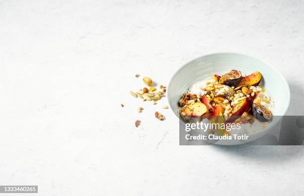breakfast bowl of yogurt with peaches, figs, nuts and seeds on white background - pfirsichkern stock-fotos und bilder
