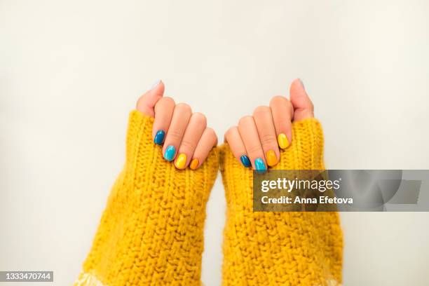 trendy bright manicure on woman hands in illuminating yellow knitted sweater against ultimate gray background. trendy colors of the year 2021. flat lay style. close-up - multi coloured nails stock pictures, royalty-free photos & images